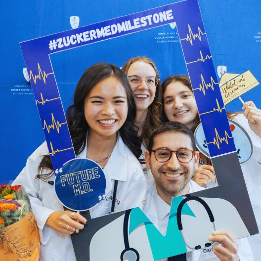 Students wearing white coat holding up signs